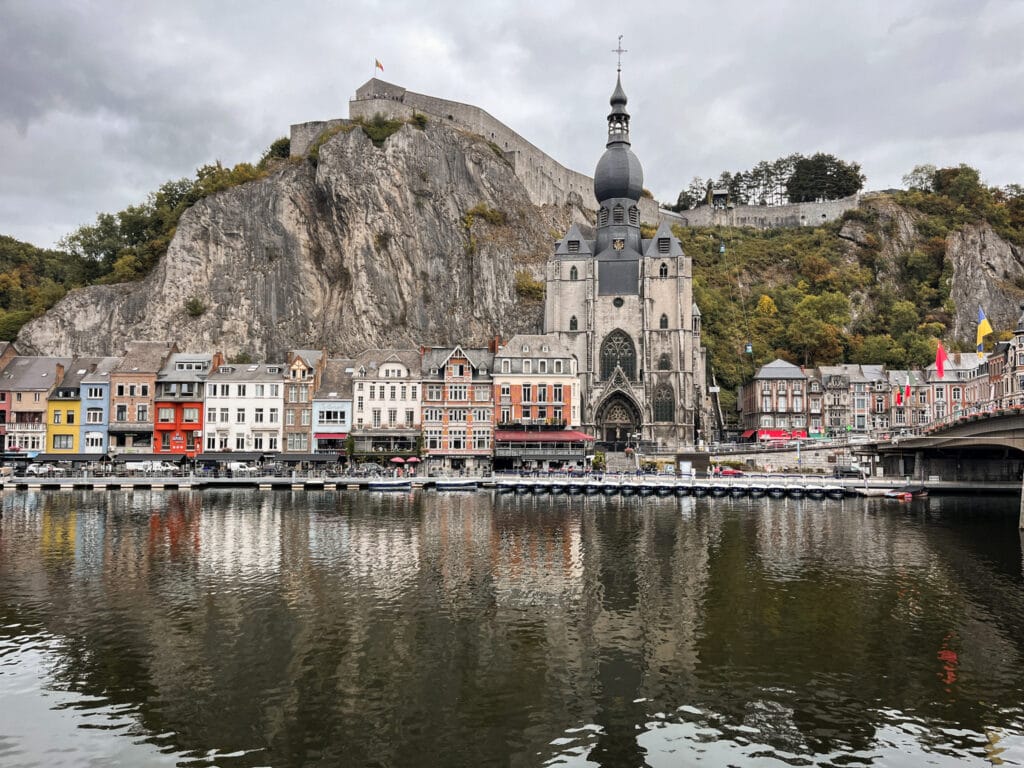 IMG_8040-Edited-27 Colorful buildings on a riverside next to a gothic style church with a stone mountain in the background.