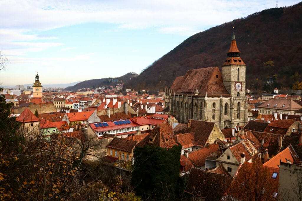 patron-catalin-HDpzCYpHp8M-unsplash old town with orange roofs against a mountain backdrop